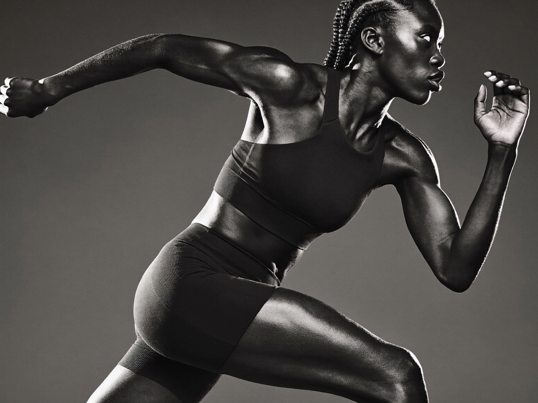 Athlète en brassière de sport et short de compression lancée en pleine foulée, photo en noir et blanc